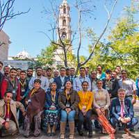 Gruppenfoto auf einem mit Bäumen bestandenen Platz vor einer Kirche 
